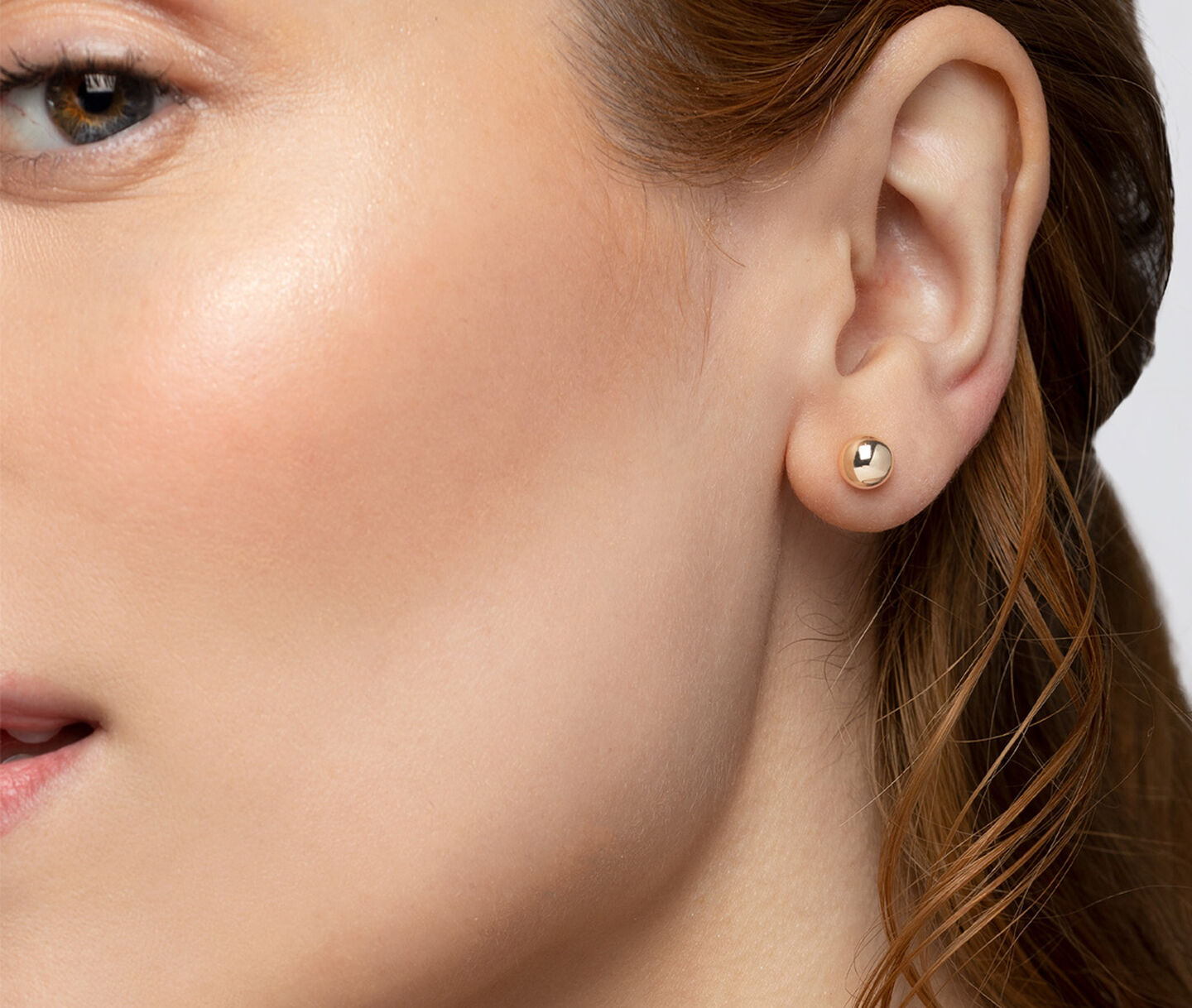 A woman wearing Birks Essentials gold stud  earrings.